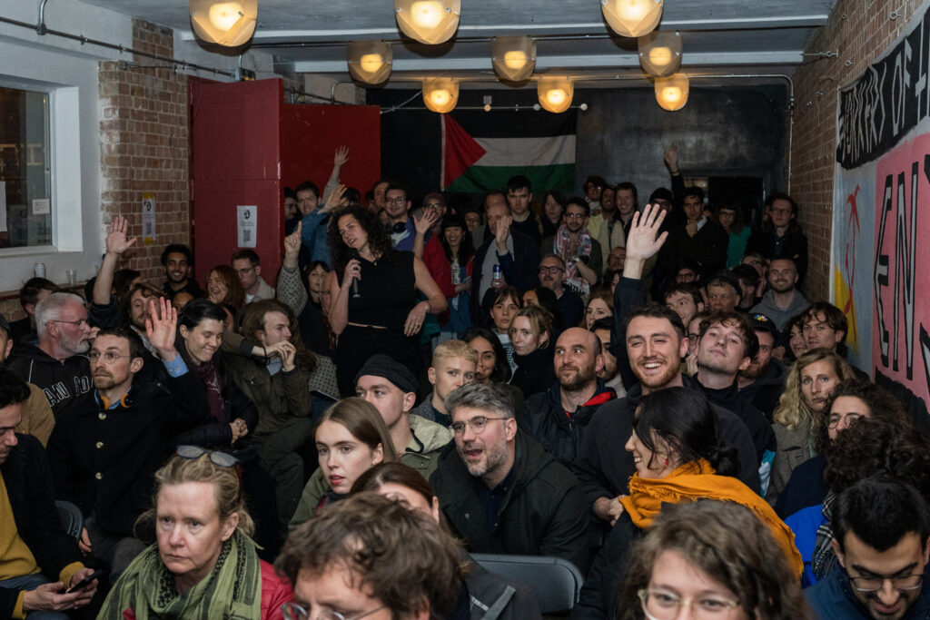 A women speaking on a microphone in a very crowded hall