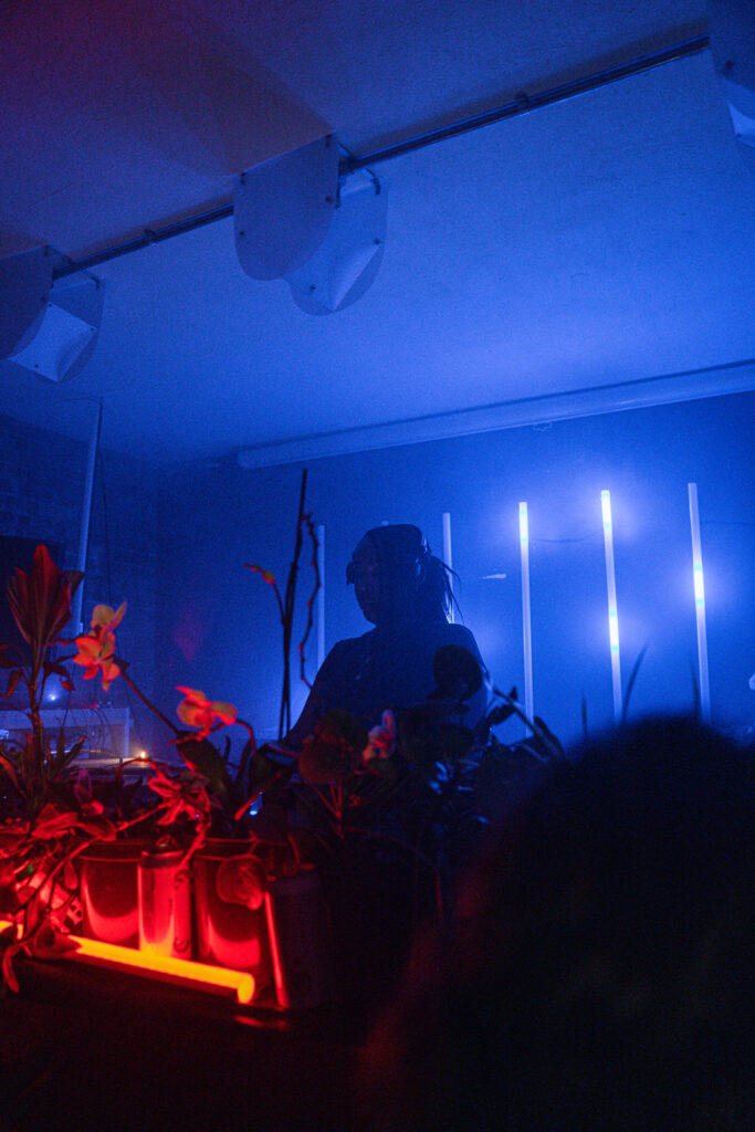 OK Williams behind a DJ tables with dramatic club lighting